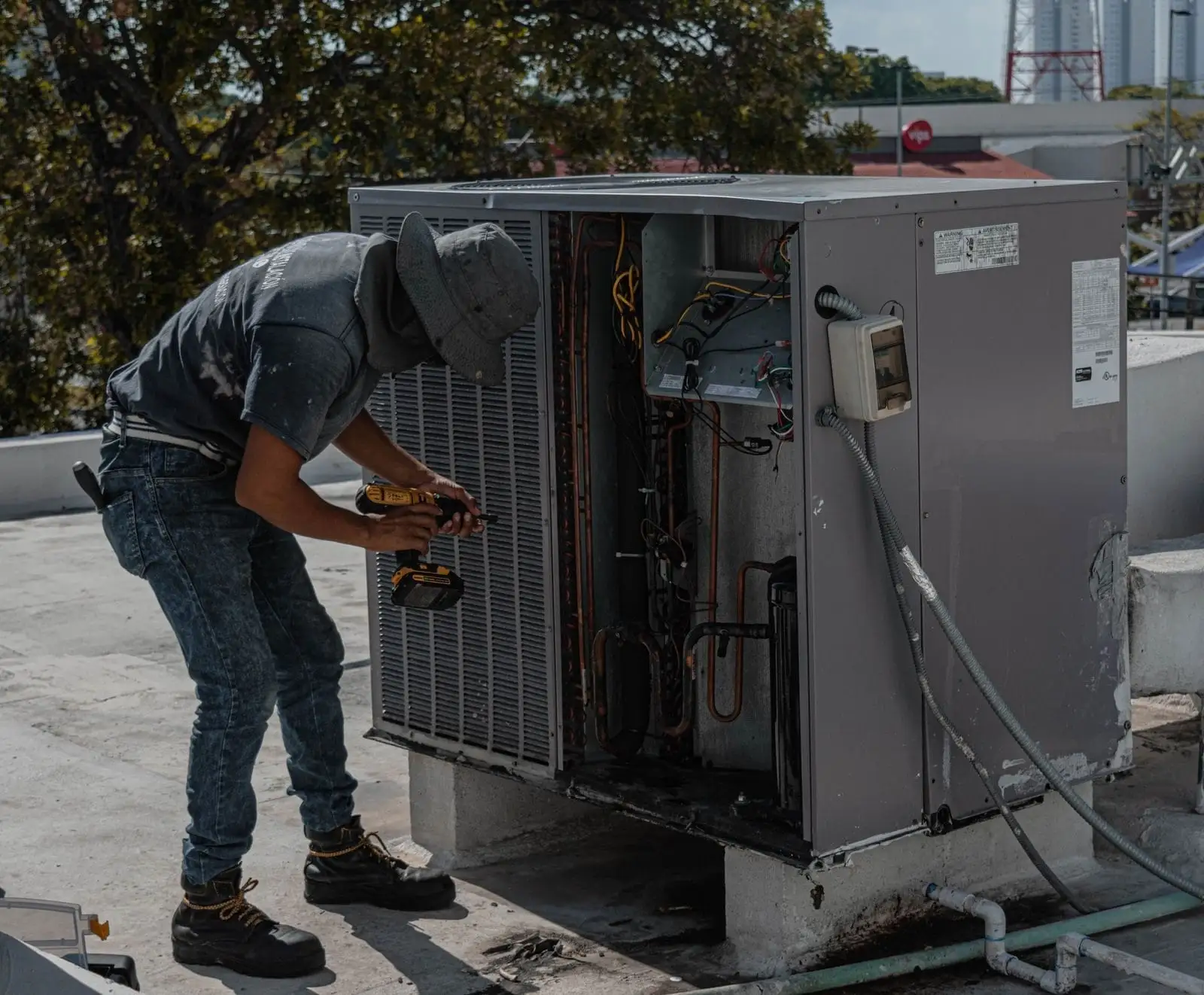 Technician servicing an open rooftop packaged unit